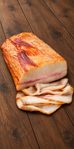 Pork fatback, shown whole and thinly sliced on dark rustic wood. Explore pork fatback and Hungarian deli meats at OstryStefek.pl.