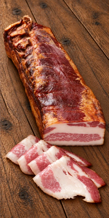 Węgierski boczek z mangalicy Palatin Mangalica kolozsvári w kawałku i plastrach, z wyeksponowanym przekrojem. Odkryj wędliny w OstryStefek.pl.