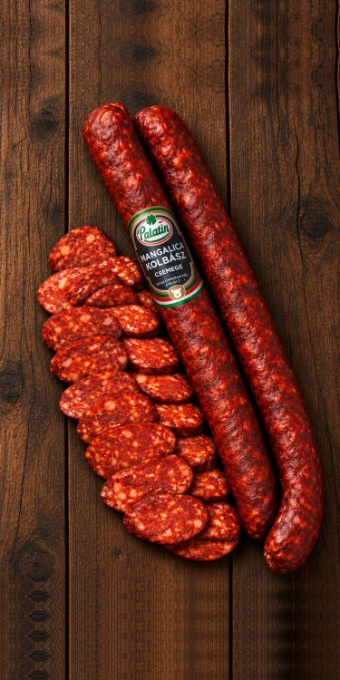 Palatin Mangalica Kolbász Csemege, a traditional mild Hungarian paprika sausage made from Mangalica pork, shown whole and sliced on rustic wooden boards.