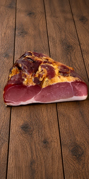 Palatin Tarjáni kereksonka half ham on rustic wooden boards, showing the cut face of the meat and a thin layer of fat.