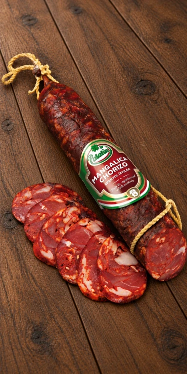 Węgierska kiełbasa Mangalica Chorizo marki Palatin, przygotowana z mięsa świni mangalicy. Aromatyczna, dojrzewająca kiełbasa w całości i plastrach na drewnianym tle.