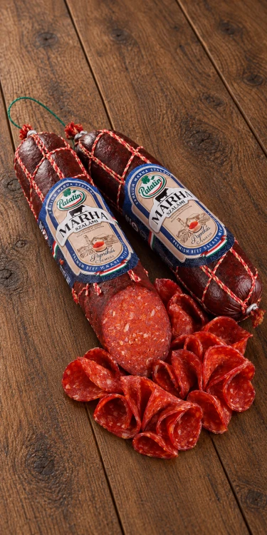 Palatin Paprikás marha szalámi csemege mild beef salami with paprika, shown whole and thinly sliced on rustic wooden boards.