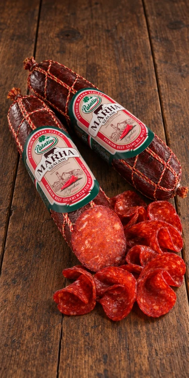 Ostre salami wołowe z papryką Palatin Paprikás marha szalámi csípős, pokazane z widocznym przekrojem i cienkimi plasterkami na rustykalnych deskach.