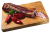A piece of dry-aged Mangalica bacon placed on a wooden board. Sliced bacon, red peppers, and parsley are arranged beside it, with light smoke visible above the product.