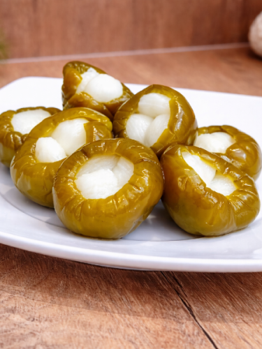 Hot pickled cherry peppers stuffed with garlic in a plastic bucket, traditional Hungarian unpasteurized vegetable pickle.