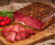 Traditional Feketekői dry-aged and smoked pork ham presented on a wooden board, showing rich color, cured slices, and gentle smoke that emphasizes its artisanal character.