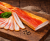Thin-sliced smoked Hungarian bacon (szalonna) with a rich, savory aroma and delicate cured texture. Paper-thin slices served on a wooden board in a rustic, elegant setup—perfect for charcuterie boards and tasting plates.