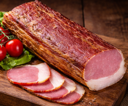 Dry-cured smoked pork loin presented in a rustic setting. Traditionally prepared, firm texture with a delicate fat layer. Perfect for sandwiches, charcuterie boards and premium cuisine.