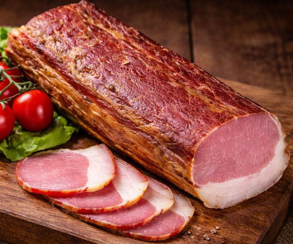 Dry-cured smoked pork loin presented in a rustic setting. Traditionally prepared, firm texture with a delicate fat layer. Perfect for sandwiches, charcuterie boards and premium cuisine.