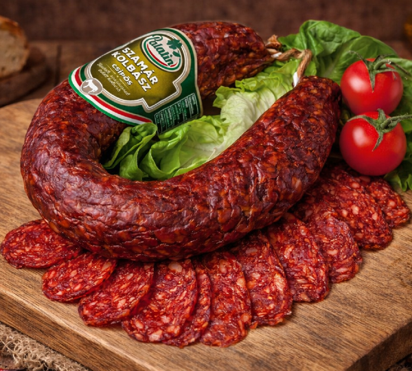 Traditional Hungarian dry-cured sausage served on a wooden board with sliced pieces, lettuce, and cherry tomatoes. Rich flavor and rustic presentation.